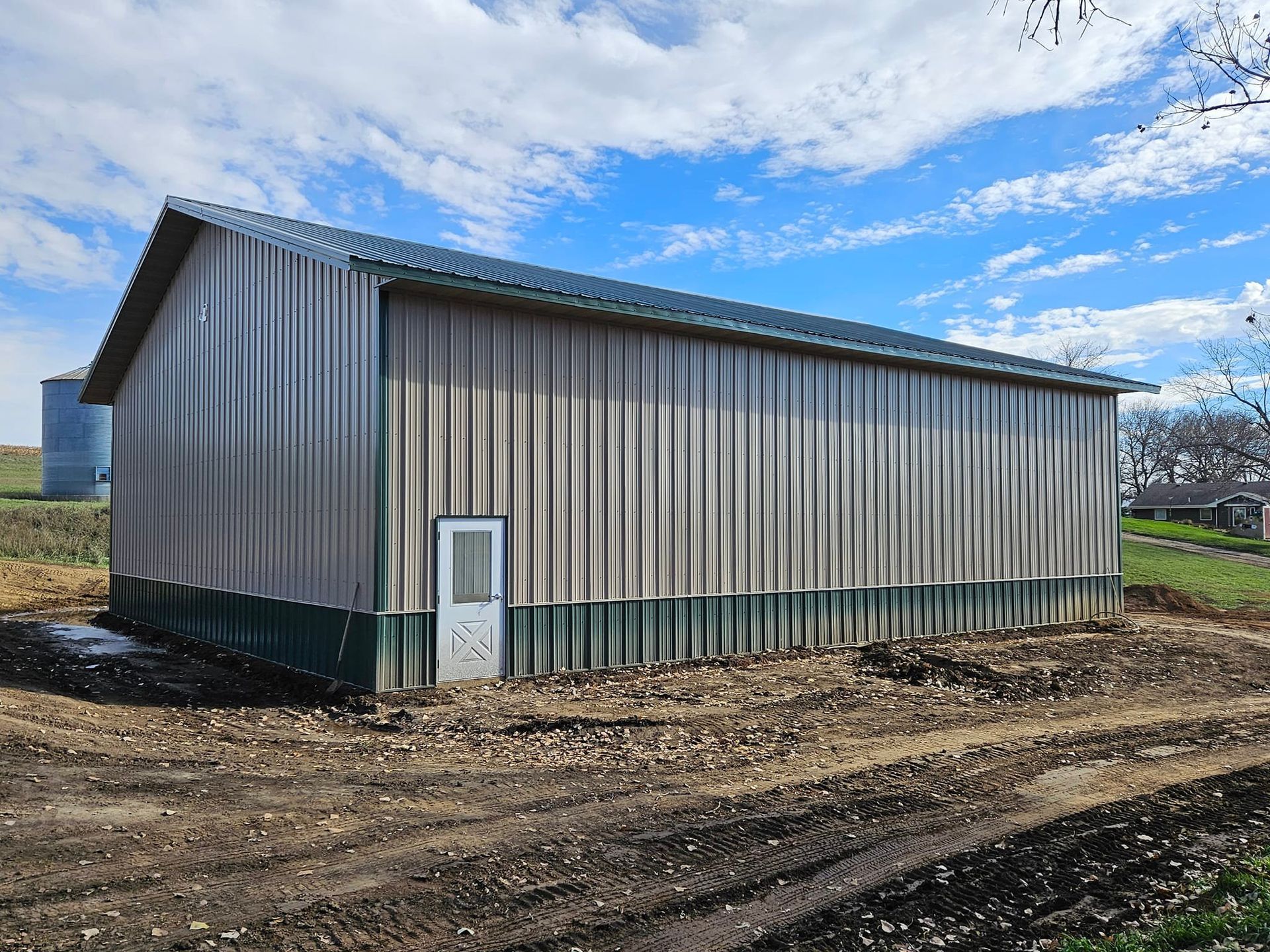 A large metal building is sitting in the middle of a dirt field.