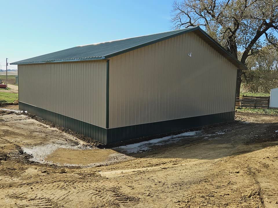 A large metal building is sitting in the middle of a dirt field.