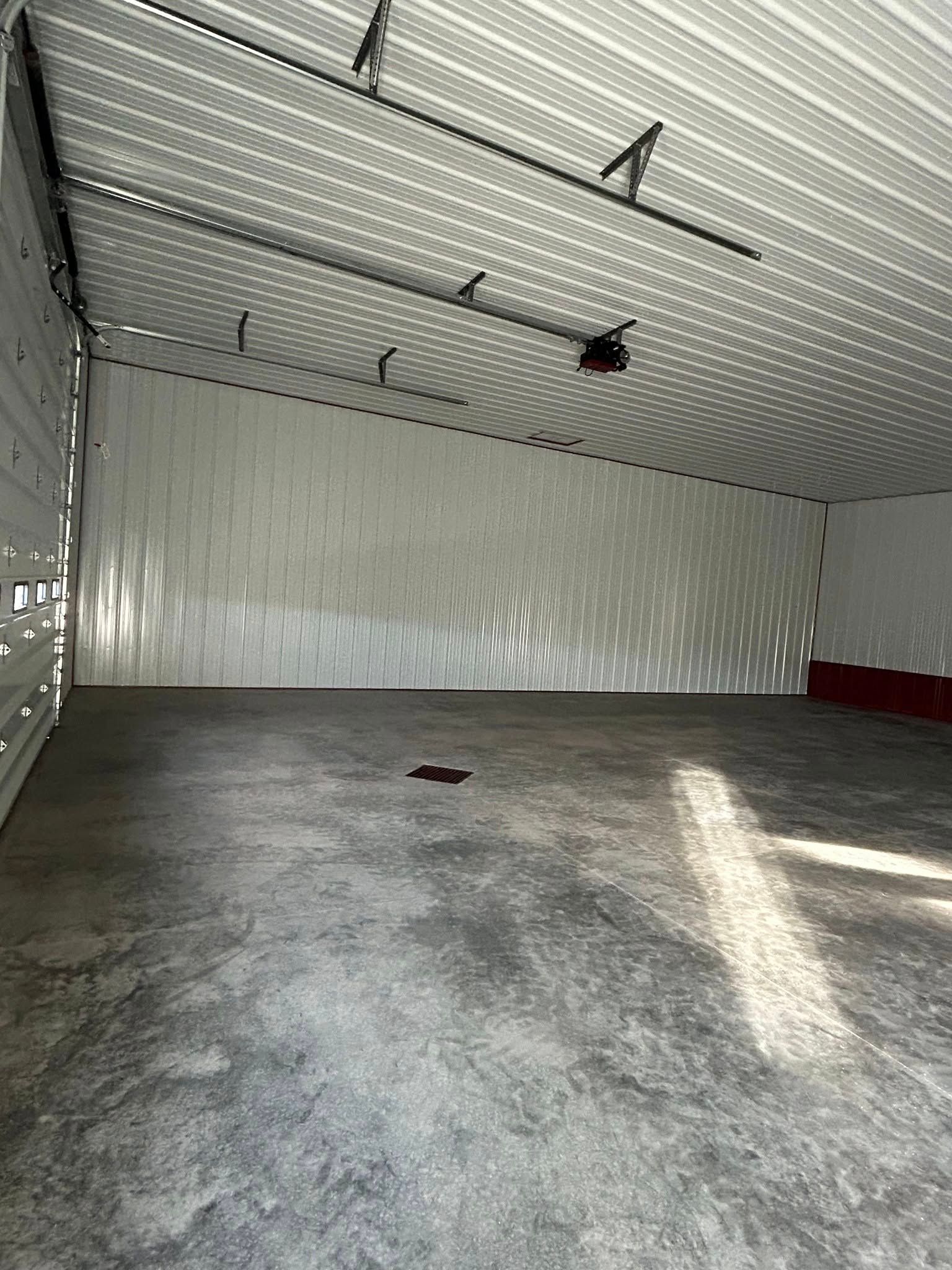 A large empty garage with a garage door open and a concrete floor.