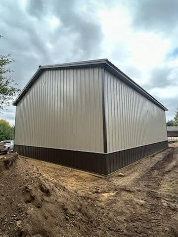 A large metal building is sitting in the middle of a dirt field.