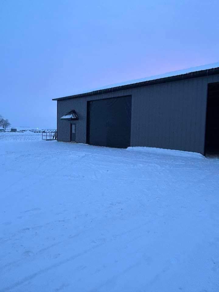 A building with a garage door is covered in snow.