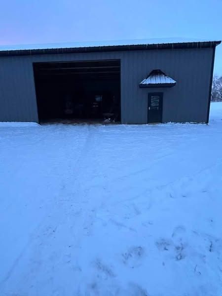 A building with a garage door is covered in snow.