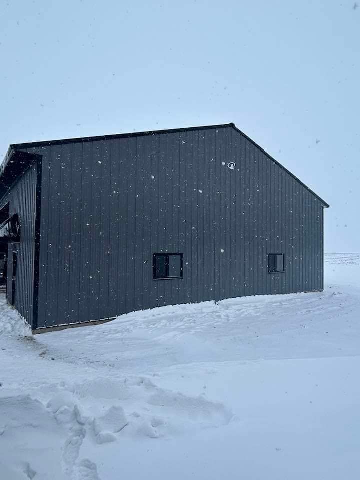 A black building is sitting in the middle of a snowy field.