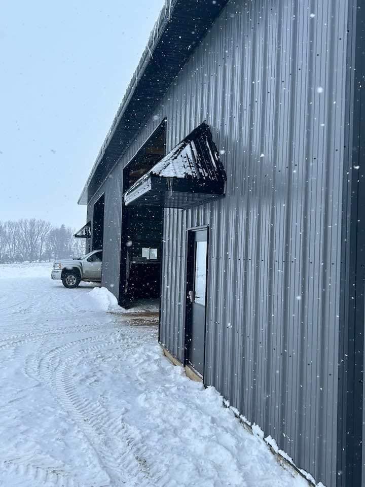A truck is parked in front of a building in the snow.