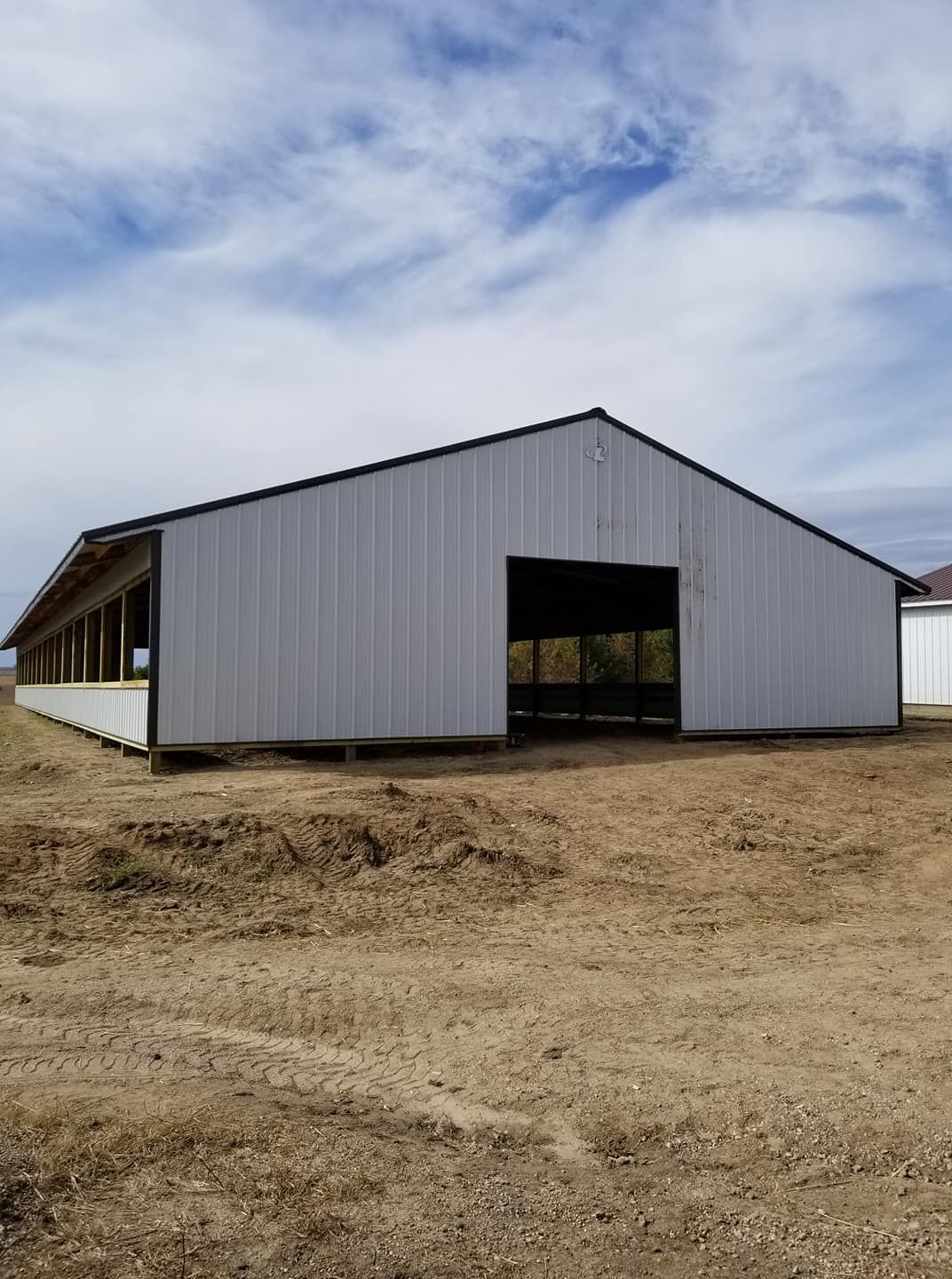 A large metal building is sitting in the middle of a dirt field.