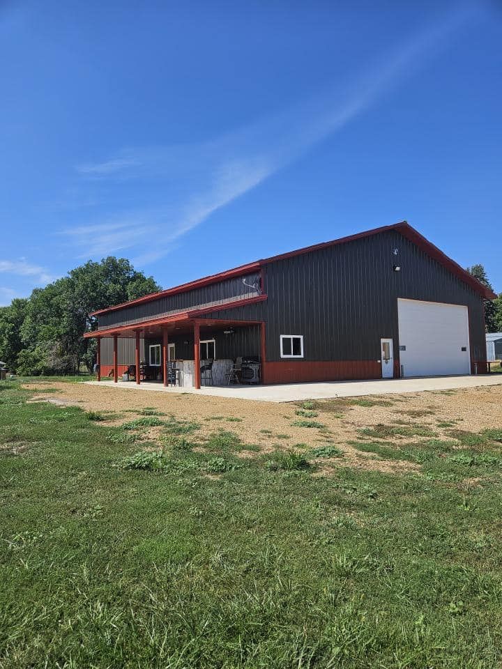 A large barn is sitting in the middle of a grassy field.