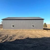 A large metal building is sitting in the middle of a field.