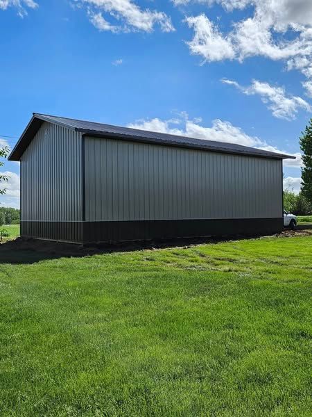 A large metal building is sitting in the middle of a lush green field.
