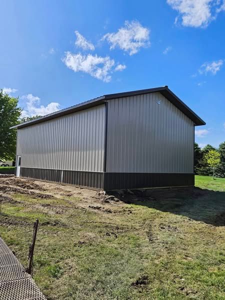 A large metal building is sitting in the middle of a grassy field.