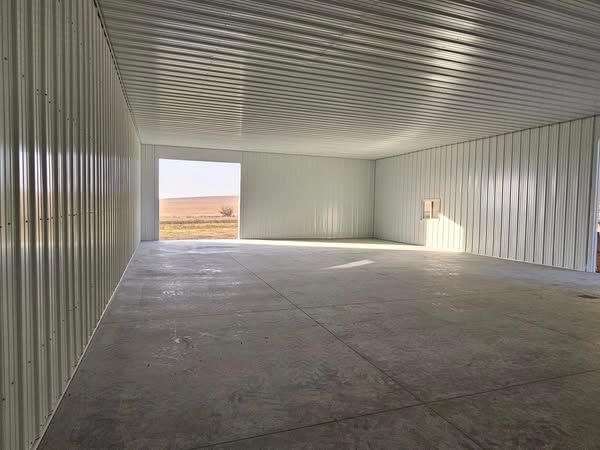 A large empty warehouse with a large door open.