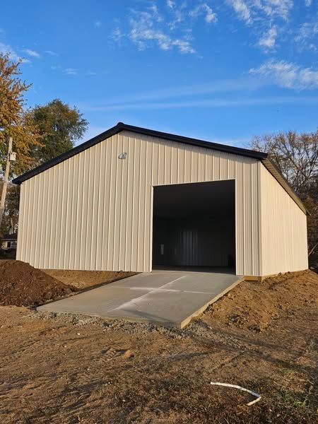 A large white building with a black roof is sitting on top of a dirt hill.