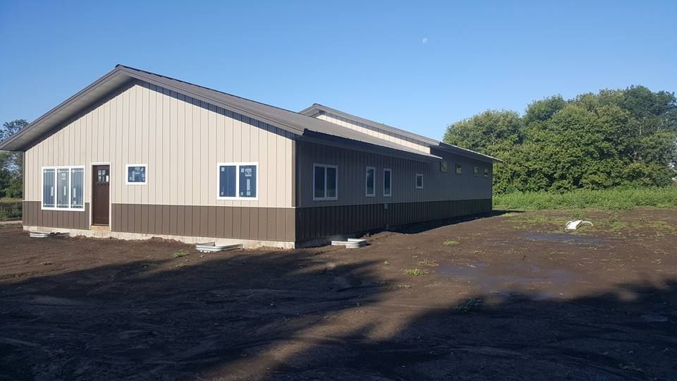 A large house is sitting in the middle of a dirt field.