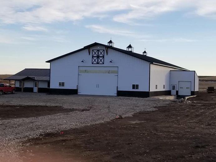 A large white barn with a red truck parked in front of it