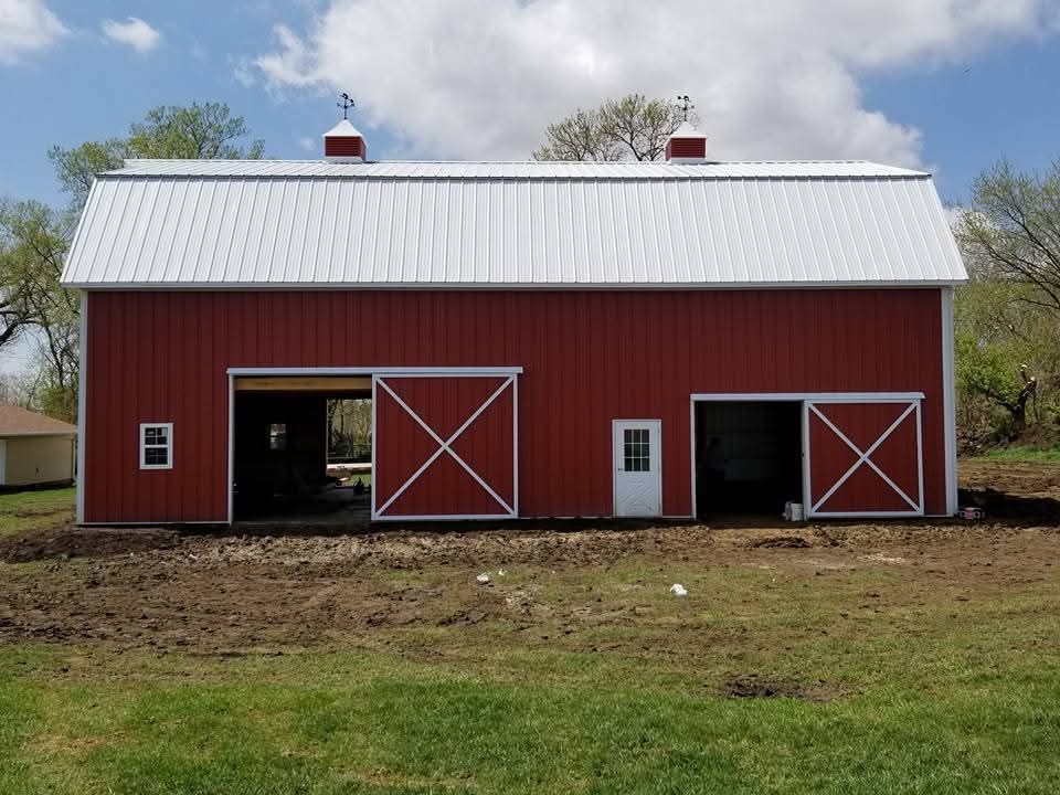 A red barn with a white roof is in a grassy field