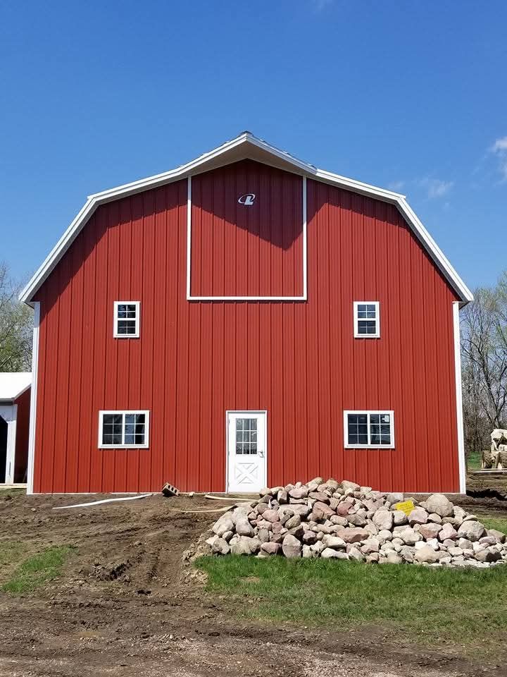 A large red barn is sitting in the middle of a grassy field.