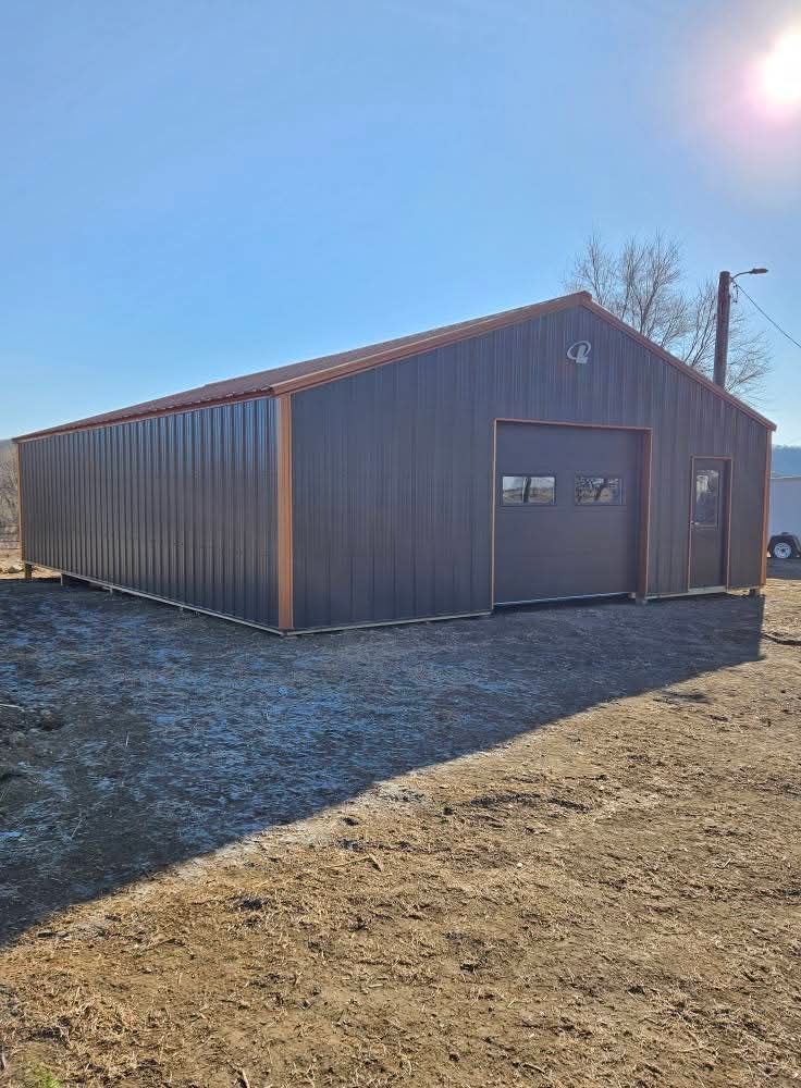 A large metal building is sitting in the middle of a dirt field.
