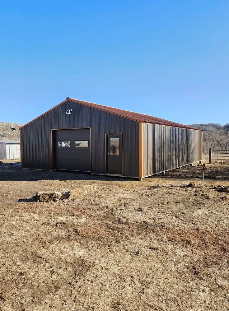 A large metal building is sitting in the middle of a dry grass field.