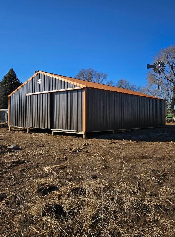 A large metal building is sitting in the middle of a field.