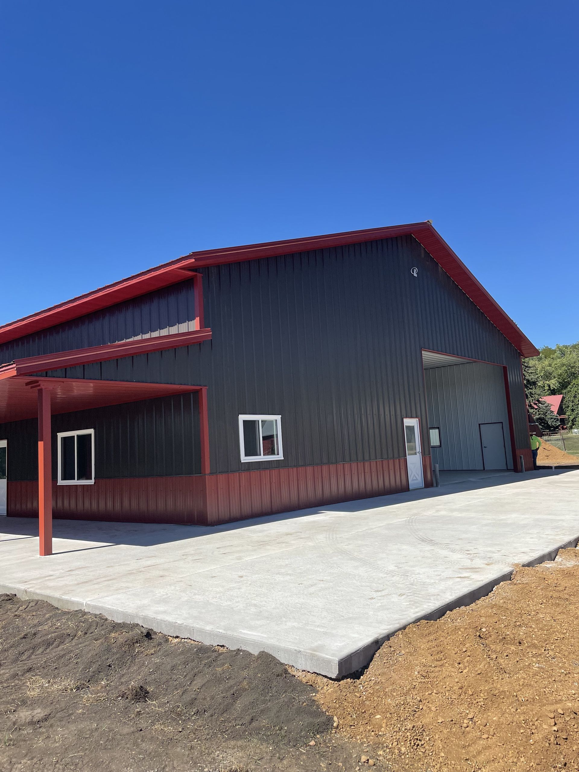 A large building with a red roof and a concrete driveway in front of it.