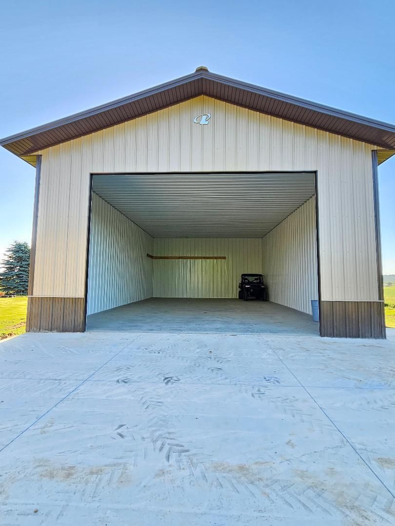 A large empty garage with a concrete driveway in front of it.
