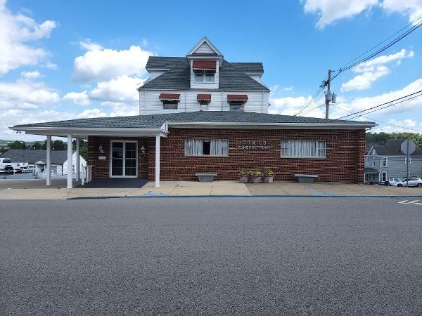 Brick train station building with a gray roof and covered porch on a sunny day