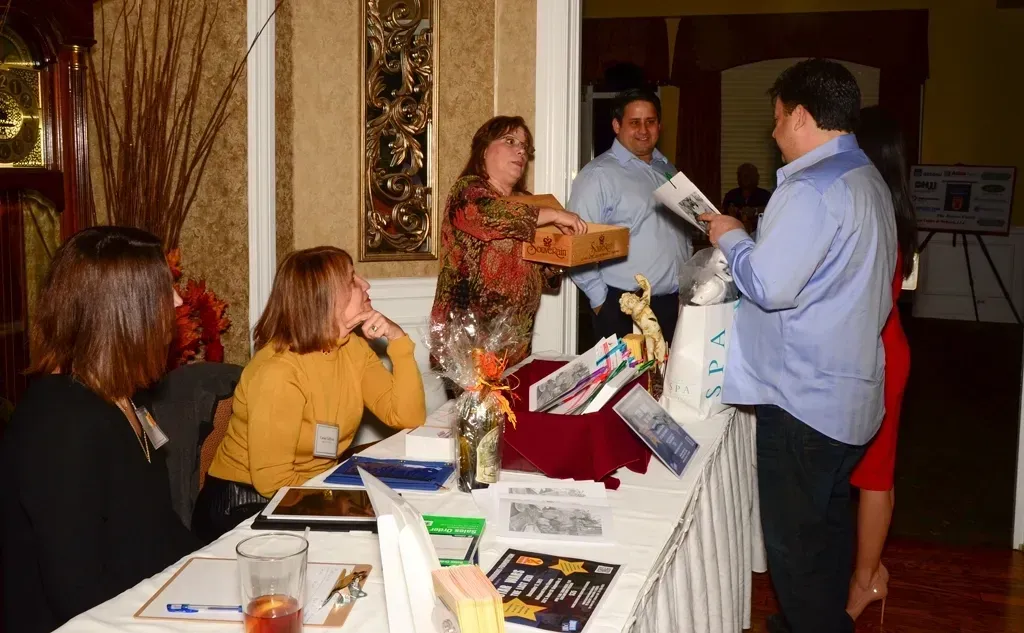People at an event registration table, handing out materials.