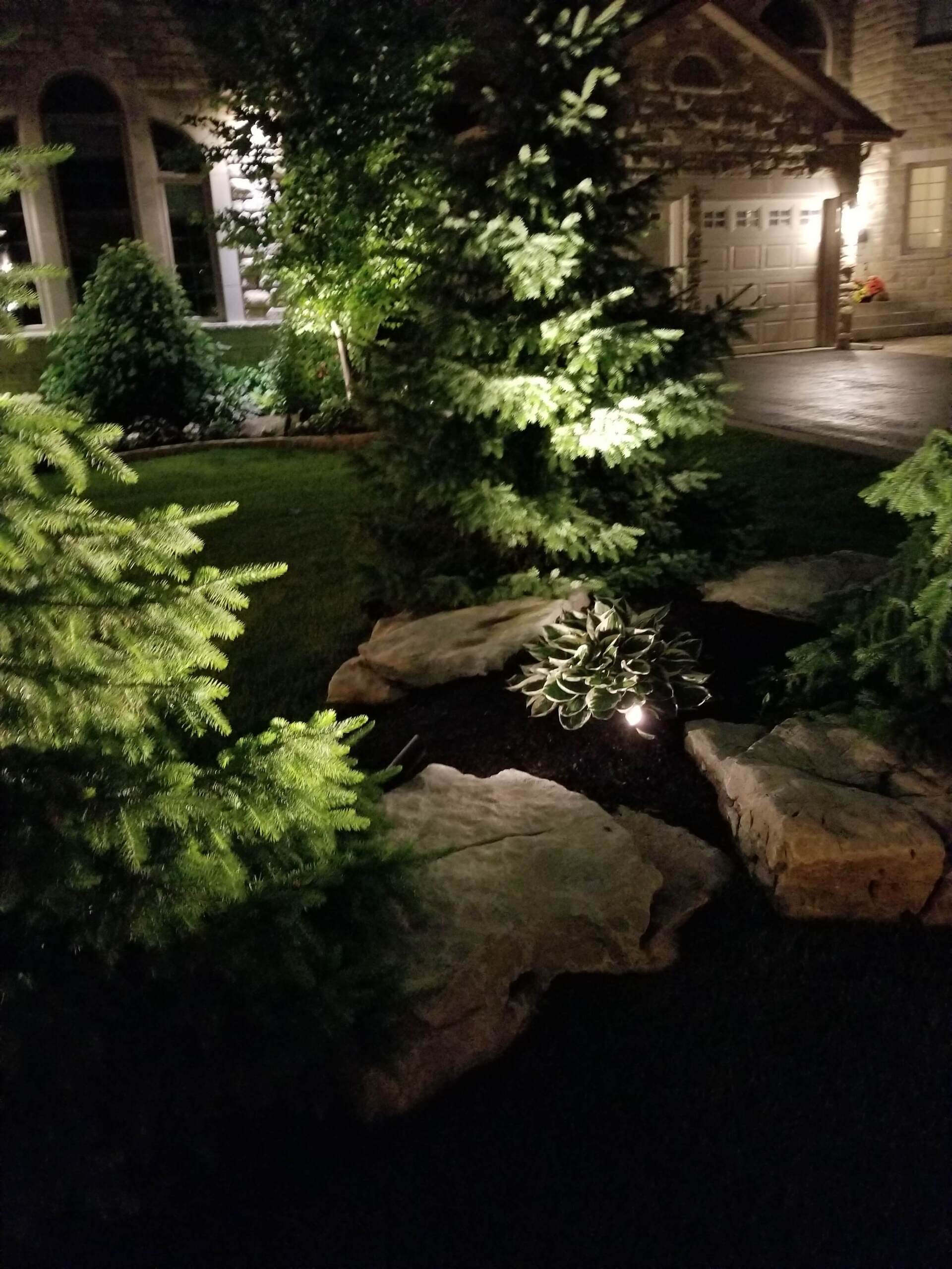 A house with a pond in front of it is lit up at night.