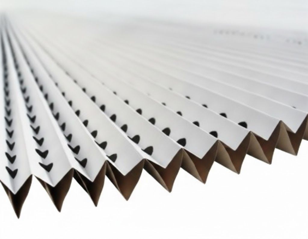Primo piano di un filtro dell'aria bianco plissettato con ritagli scuri a forma di punta di freccia.
