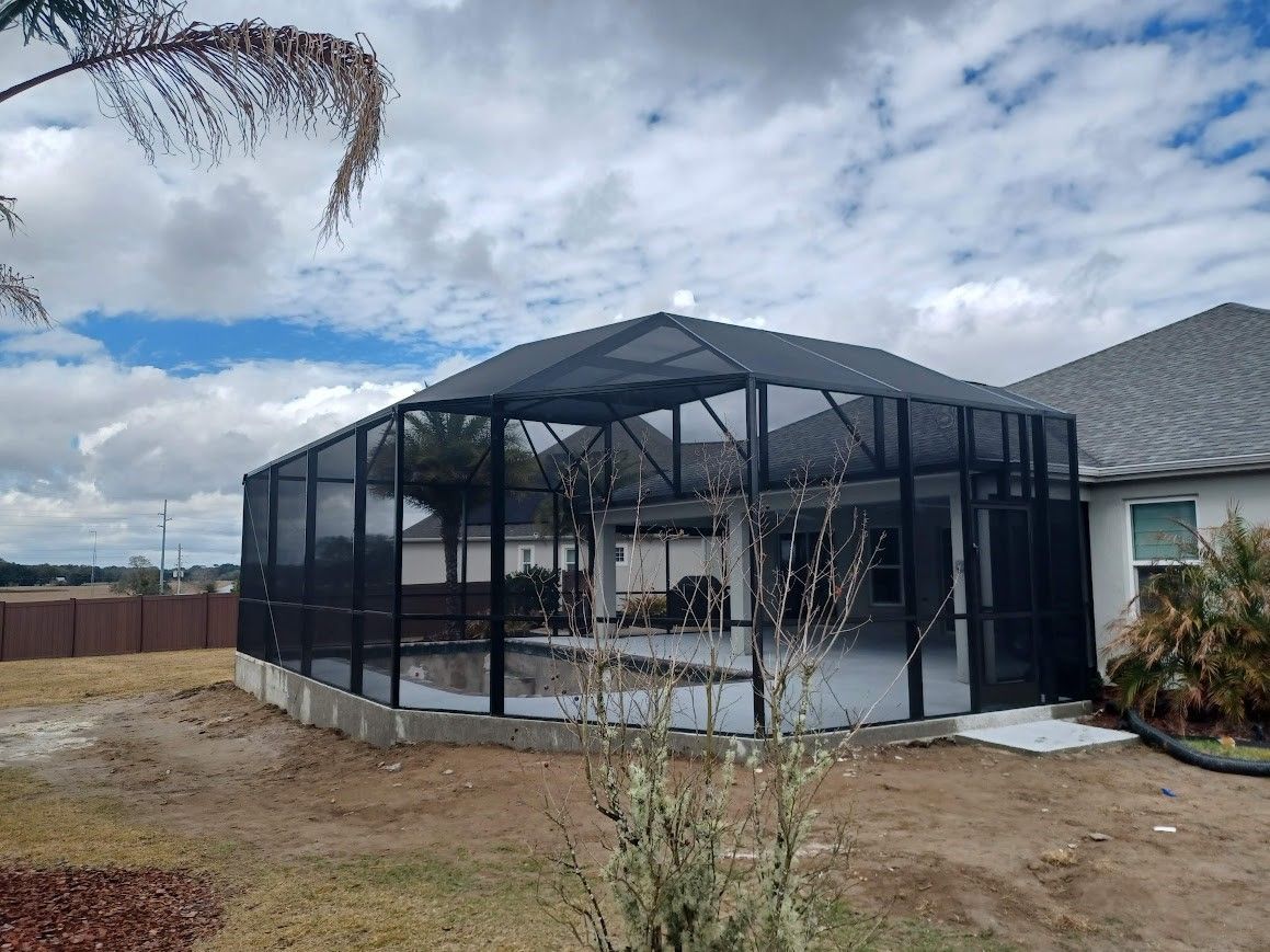 A screened in porch is being built in the backyard of a house.