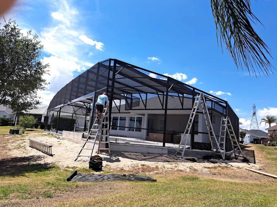 A man is standing on a ladder in front of a house under construction.