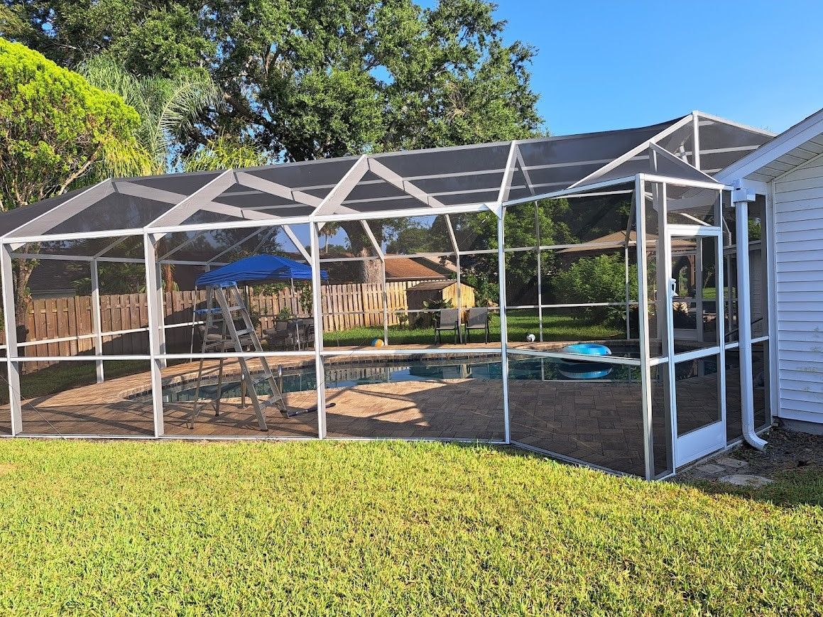 A screened in swimming pool in a backyard next to a house.