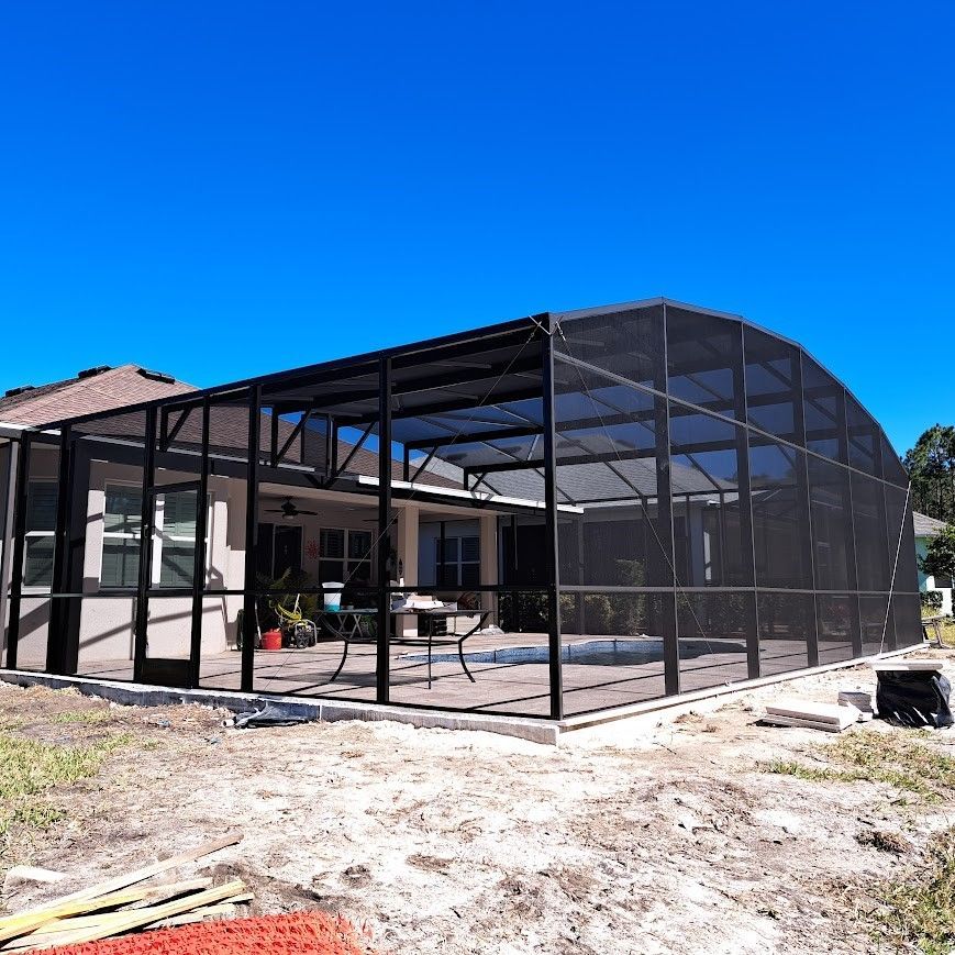 A screened in pool area is being built in front of a house.