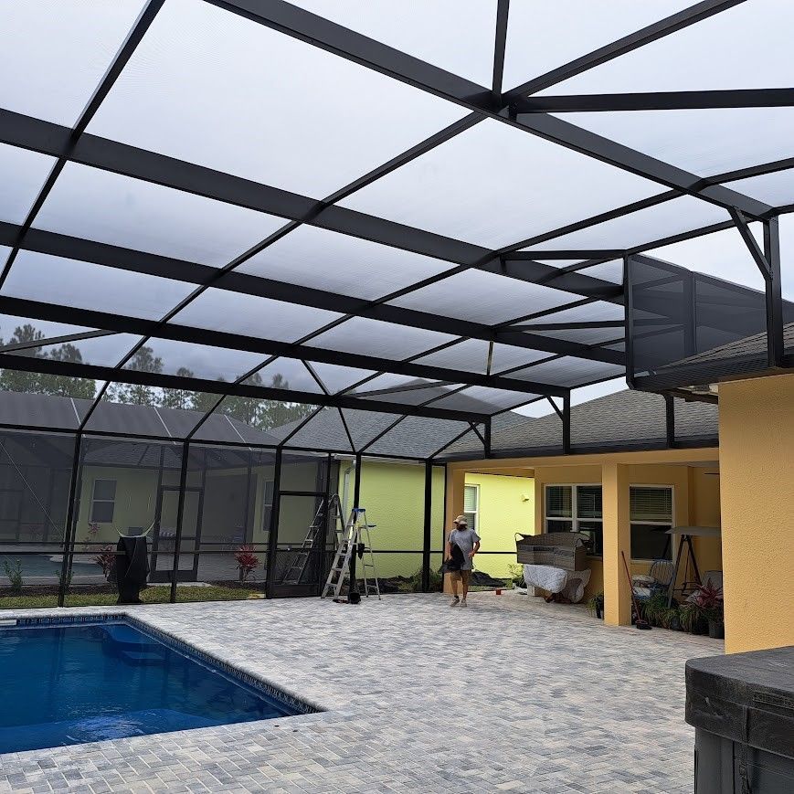 A screened in area with a pool and a house in the background