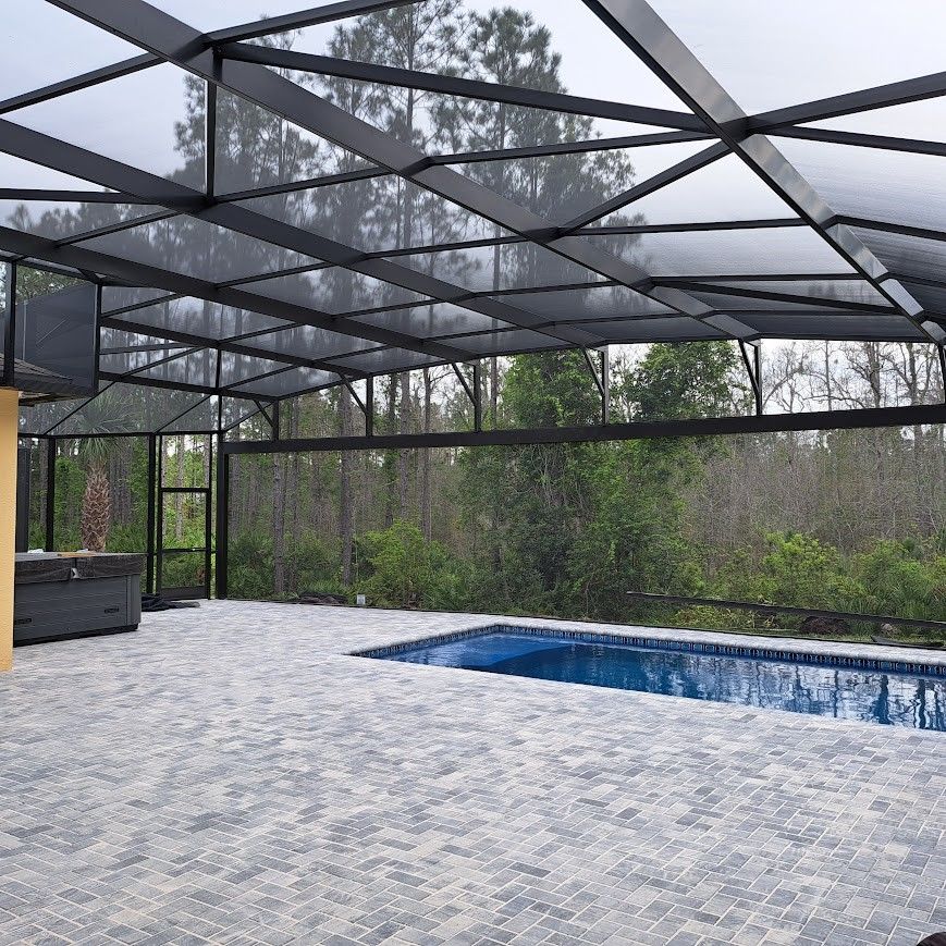 A swimming pool under a screened in area with trees in the background