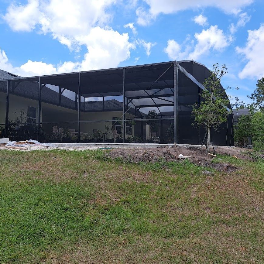 A house with a screened in porch is sitting on top of a lush green field.