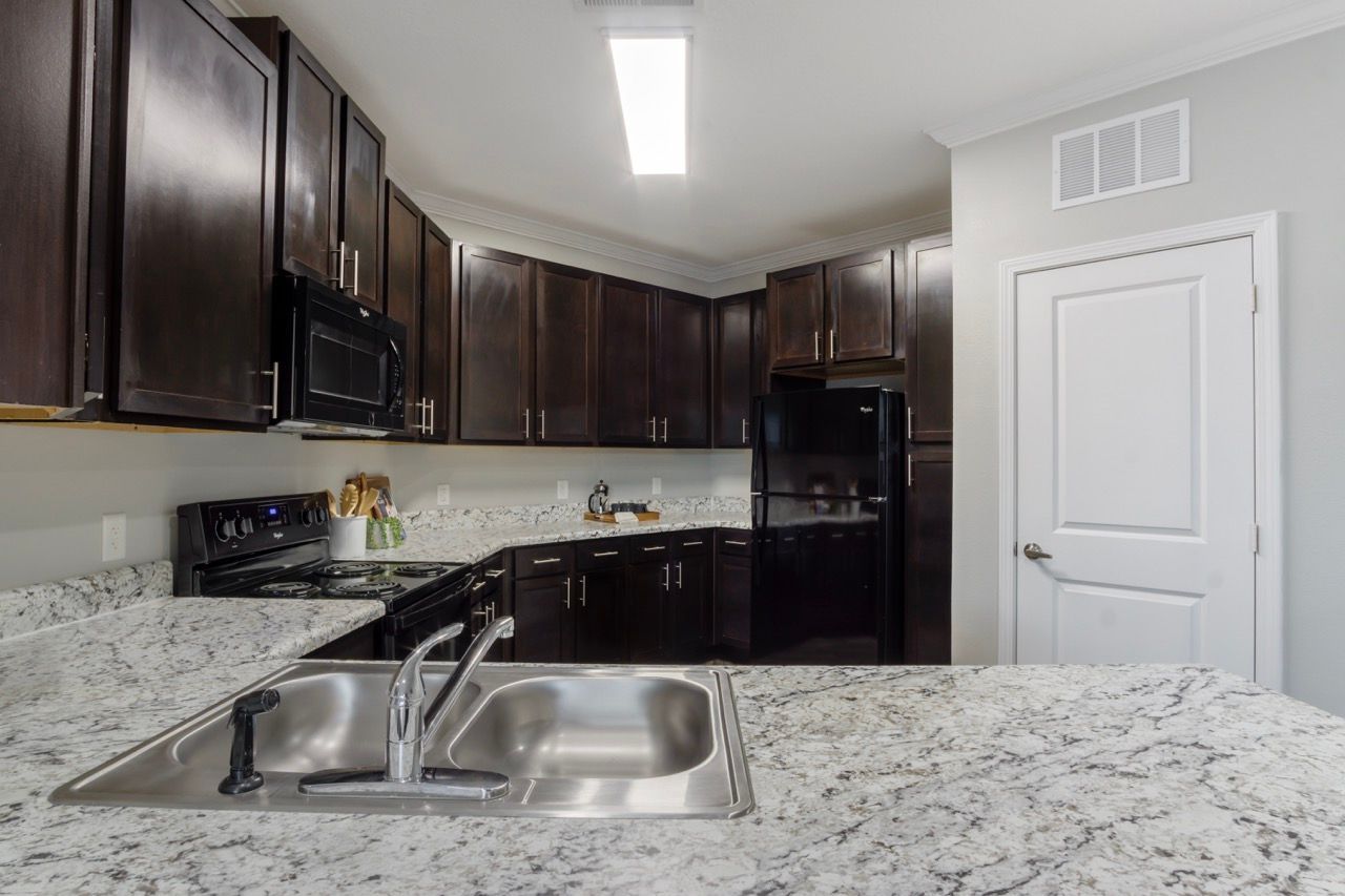 Kitchen with dark wood cabinets, granite countertops, and stainless steel appliances.
