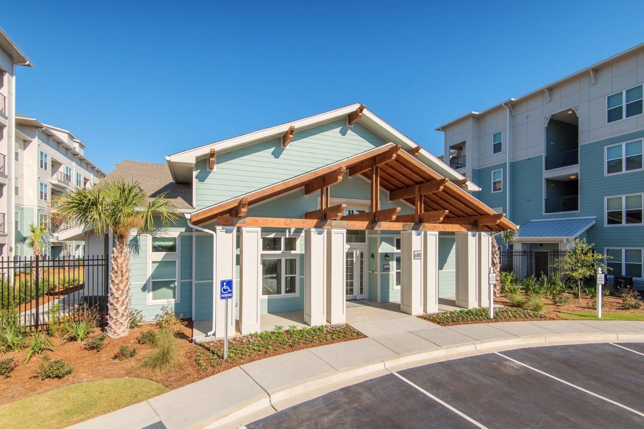 Exterior entrance to a modern apartment community with a covered entry and handicap parking sign.