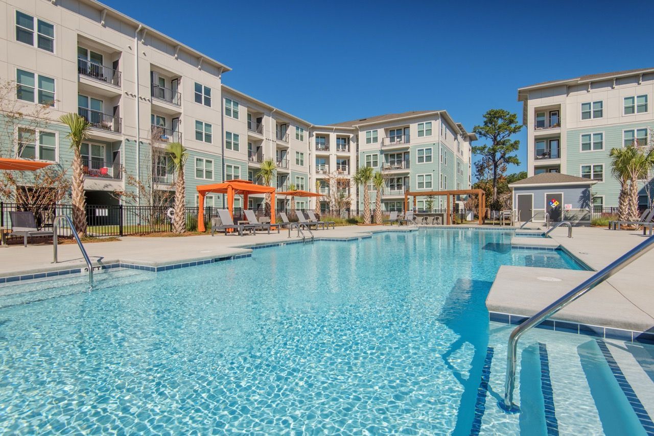 Outdoor apartment community pool with lounge chairs and pergolas.