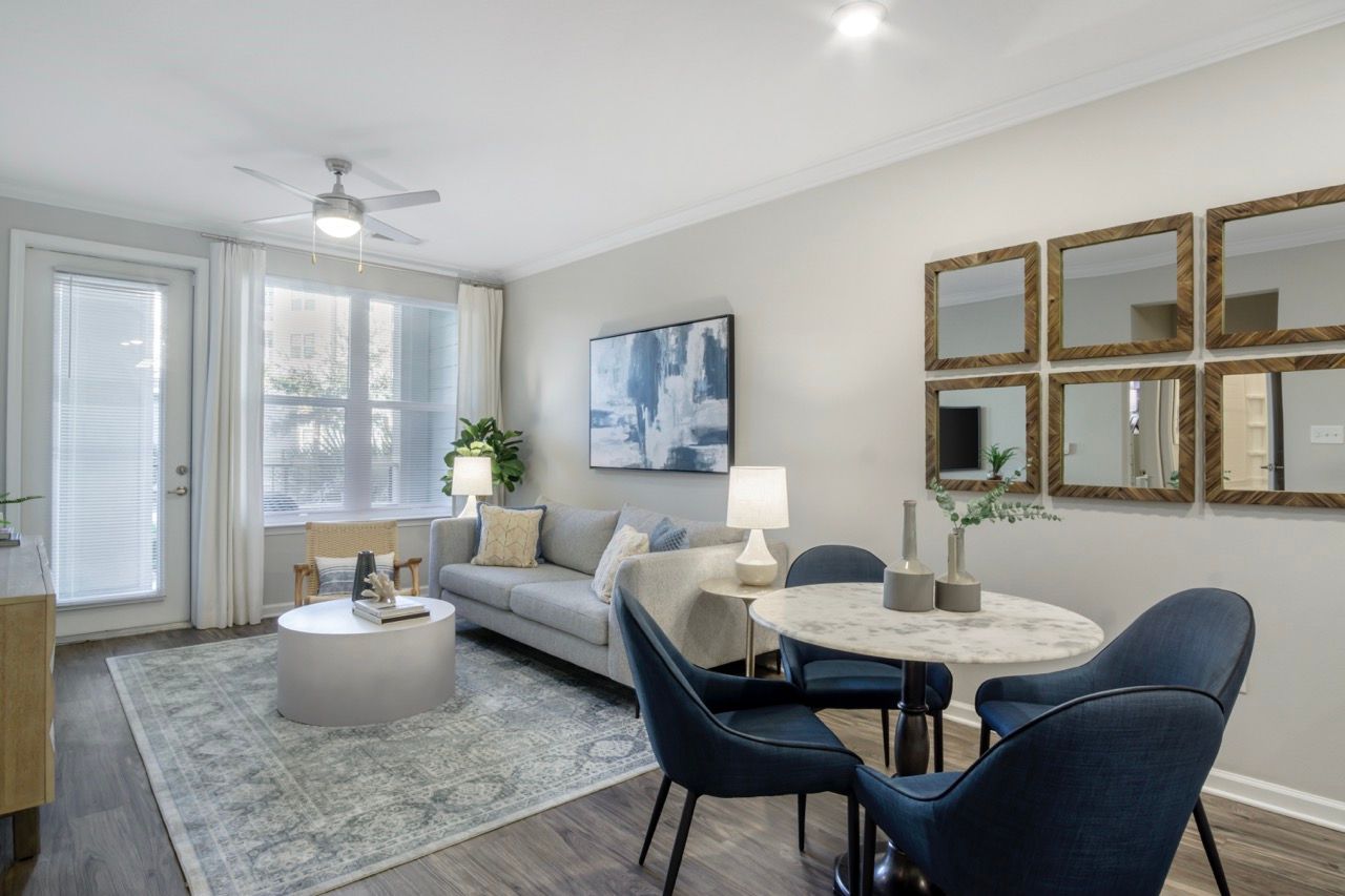 Living room of a modern apartment with a gray sofa, round marble dining table, and wall art.
