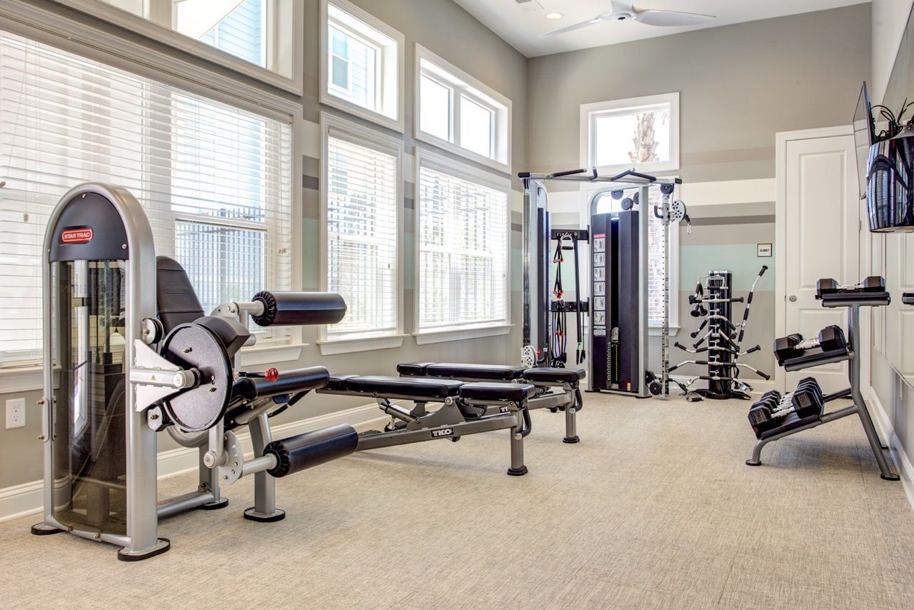 Bright community gym with weight machines, a bench, and free weights.