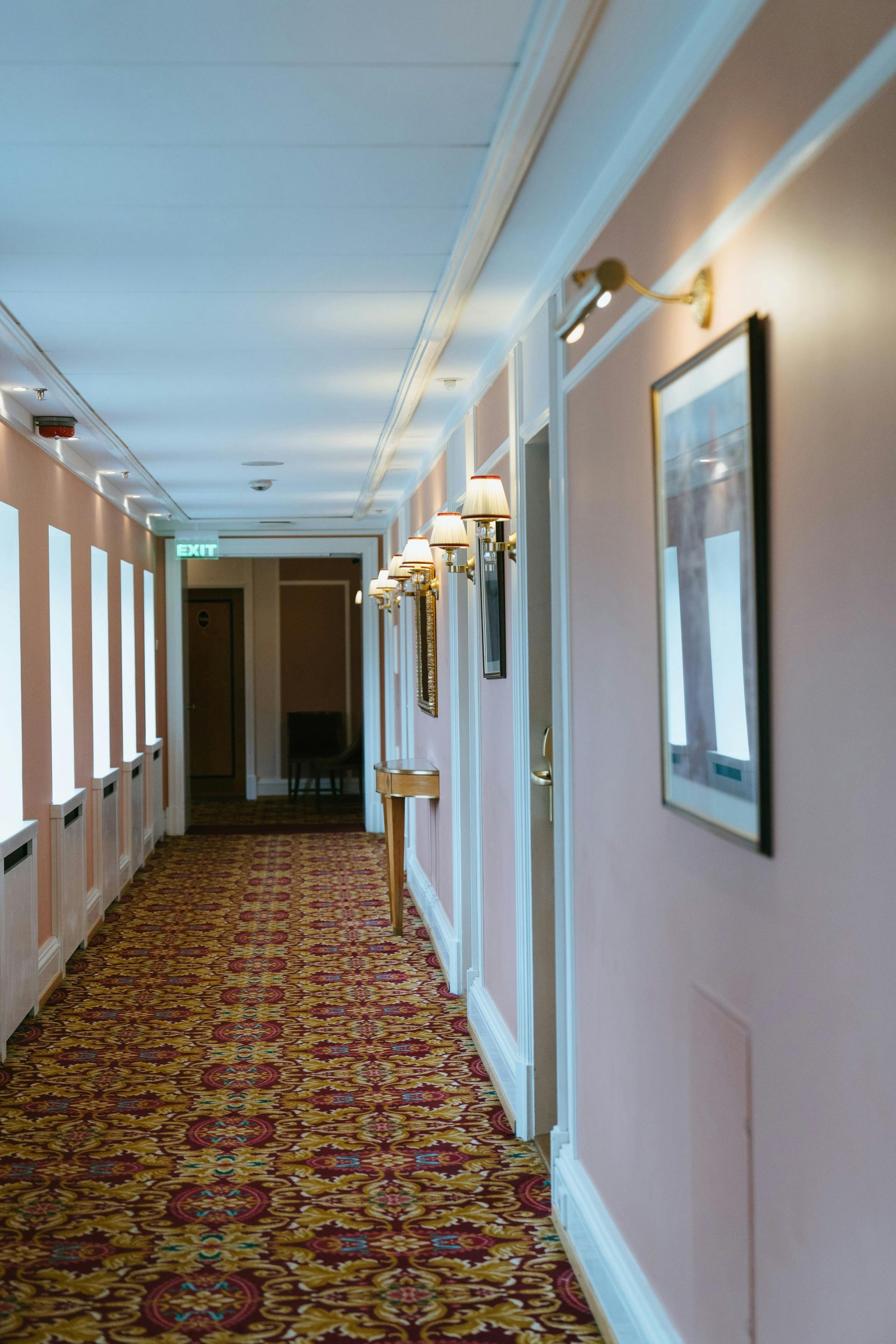 A long hallway with a red carpet and a picture on the wall.