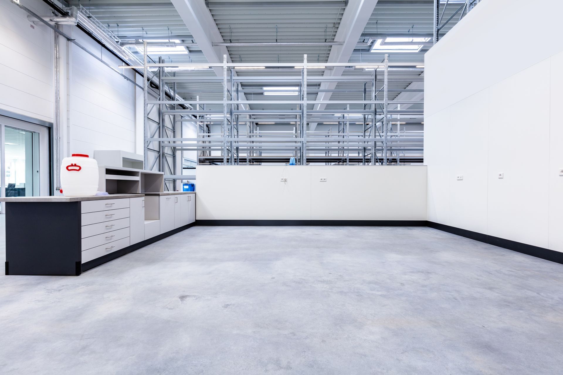 A large empty room with a concrete floor and white walls.