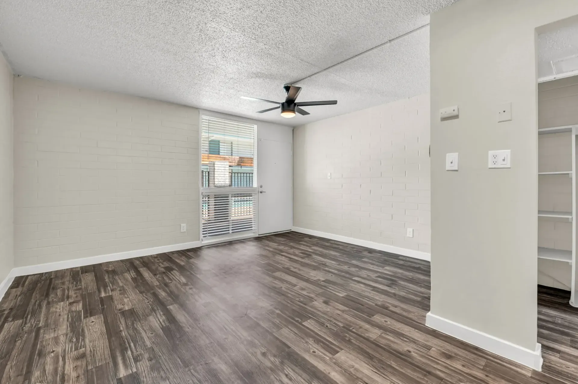 an empty room with a ceiling fan and a sliding glass door