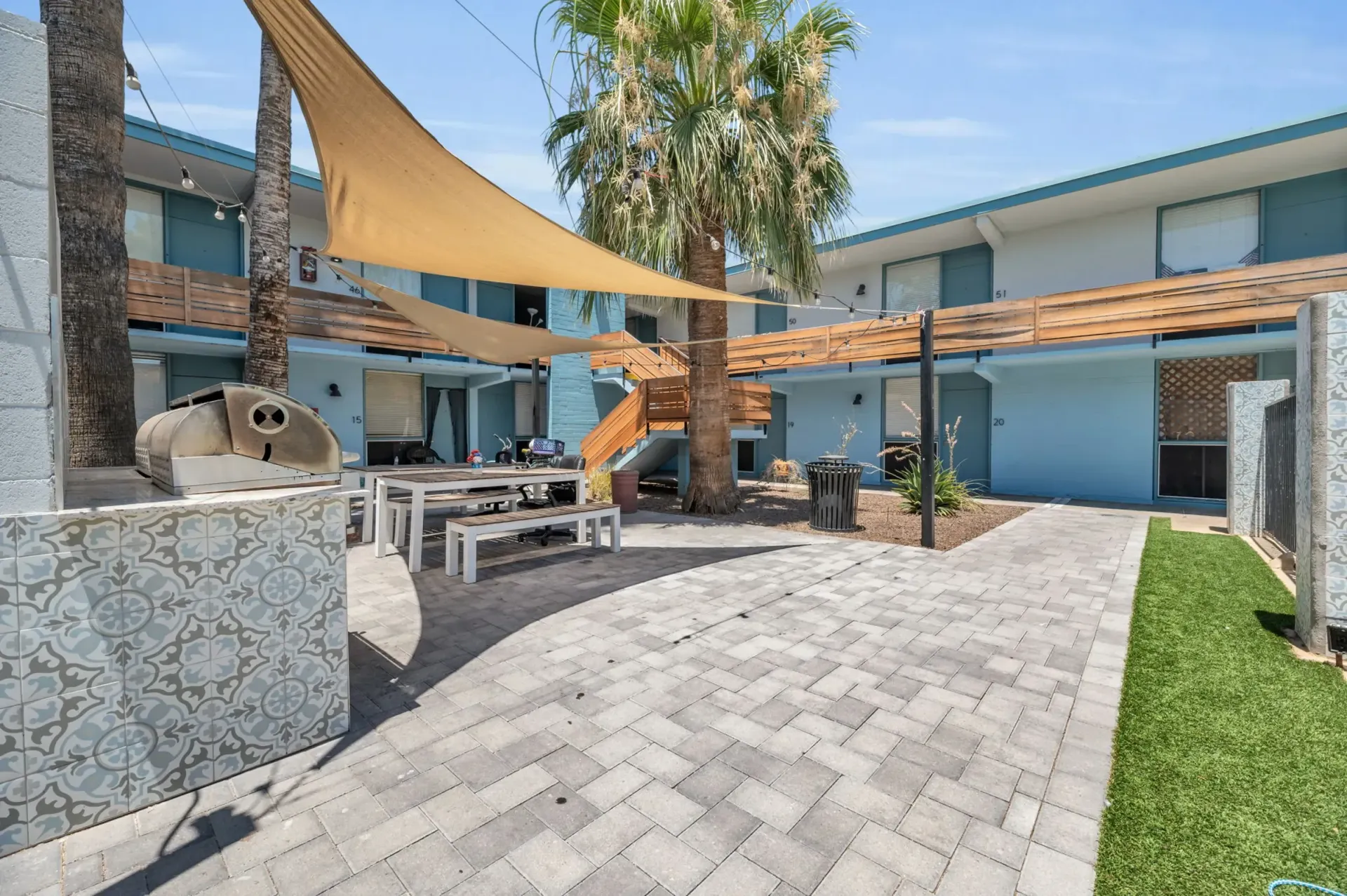 a patio with a table and chairs under a shade sail