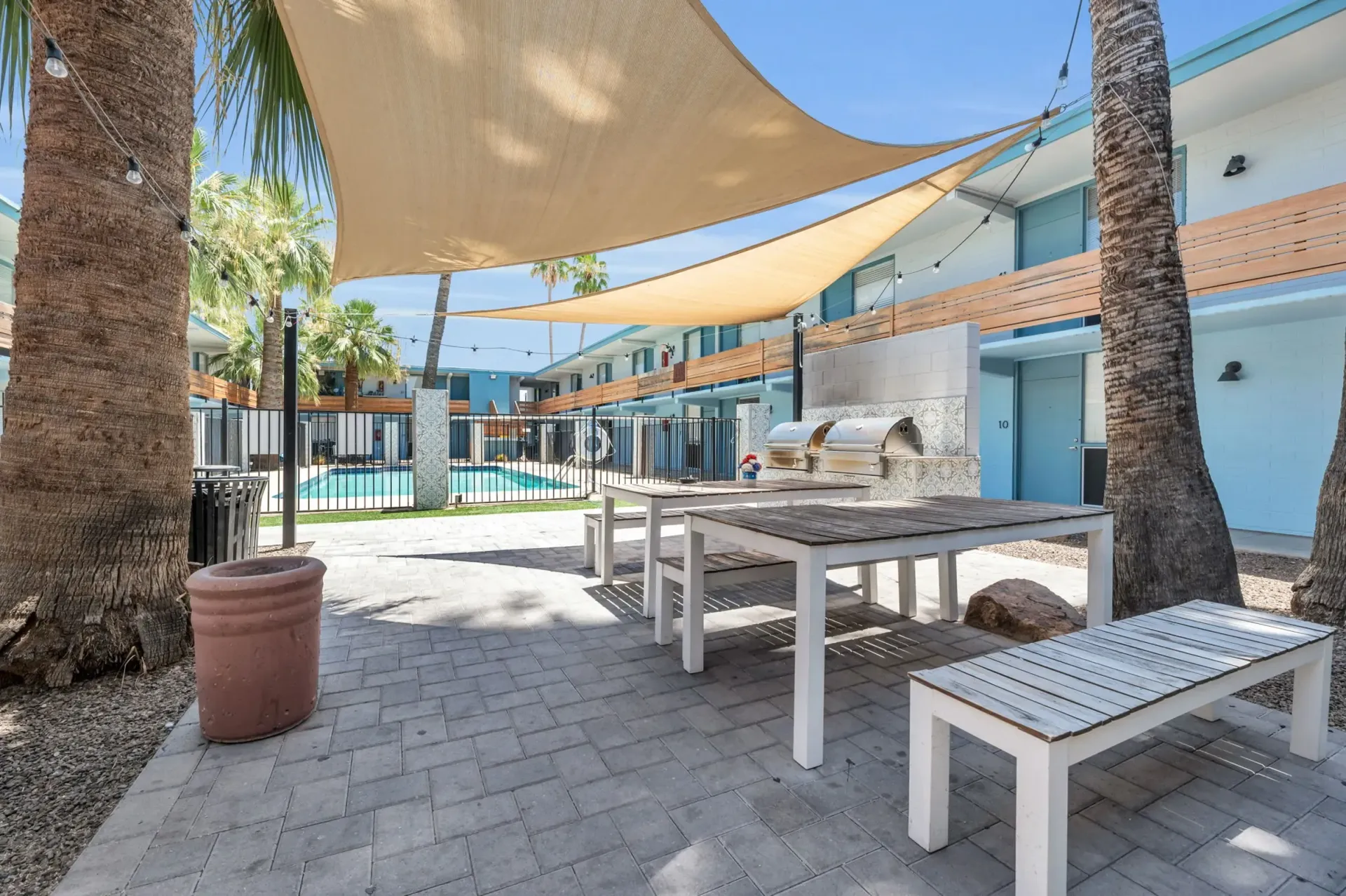 a patio with a table and benches under an umbrella
