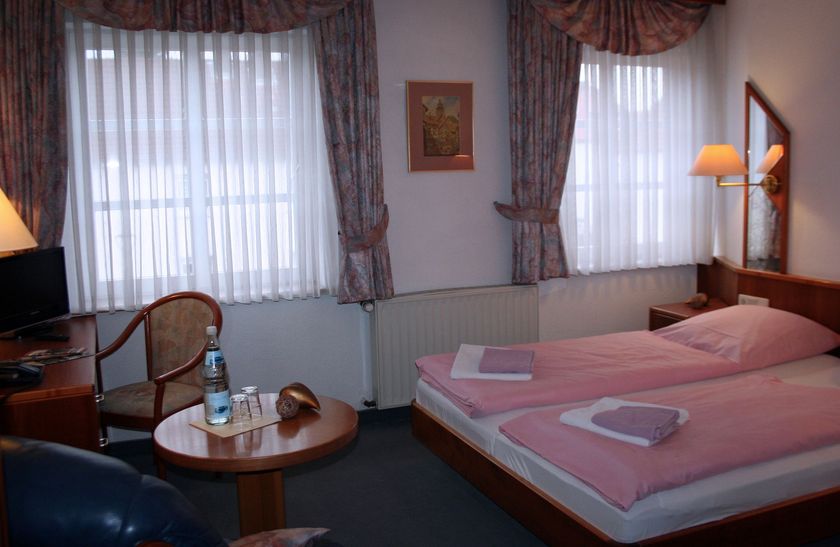 Ein Hotelzimmer mit zwei Betten und einem Tisch mit einer Flasche Wasser darauf