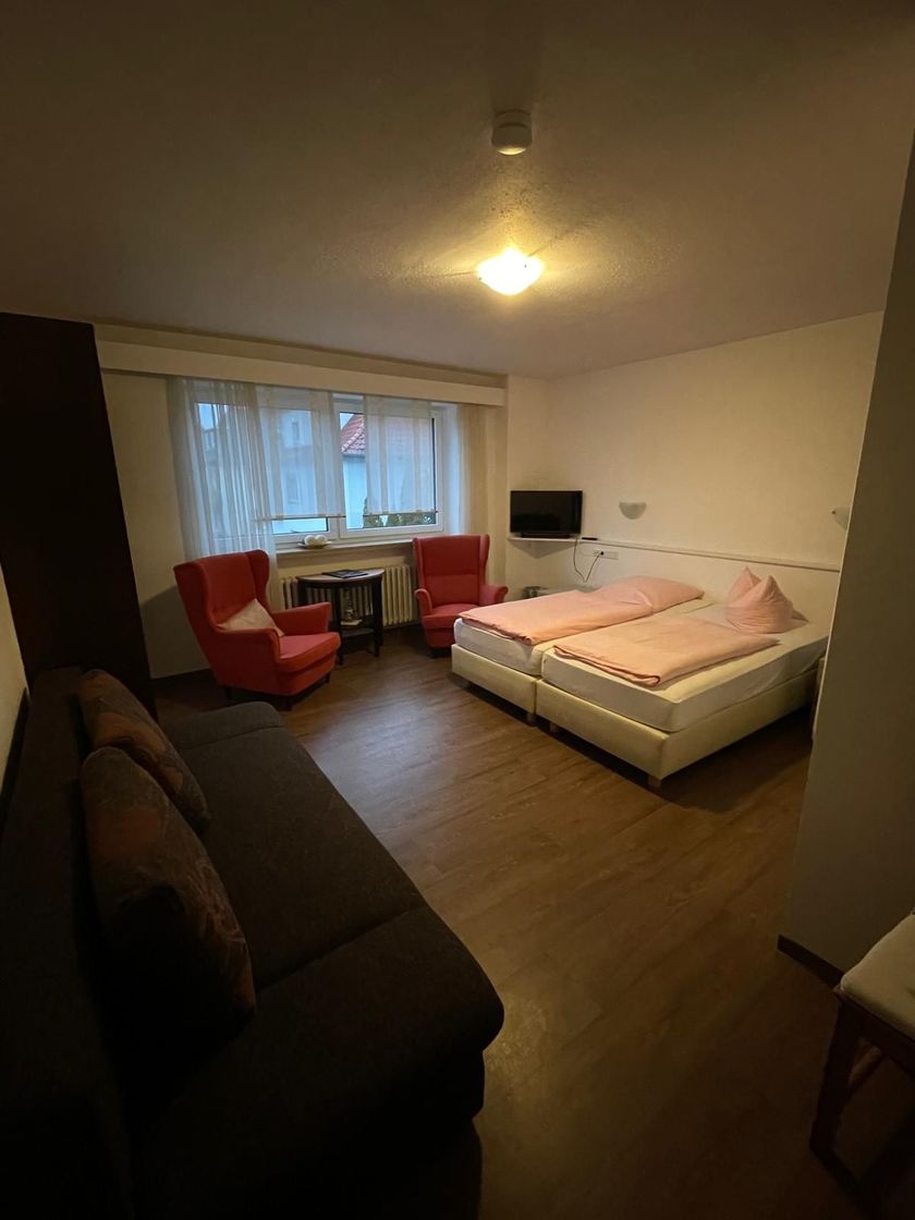 Ein Schlafzimmer mit zwei Betten, einer Couch, zwei Sesseln und einem Fernseher.