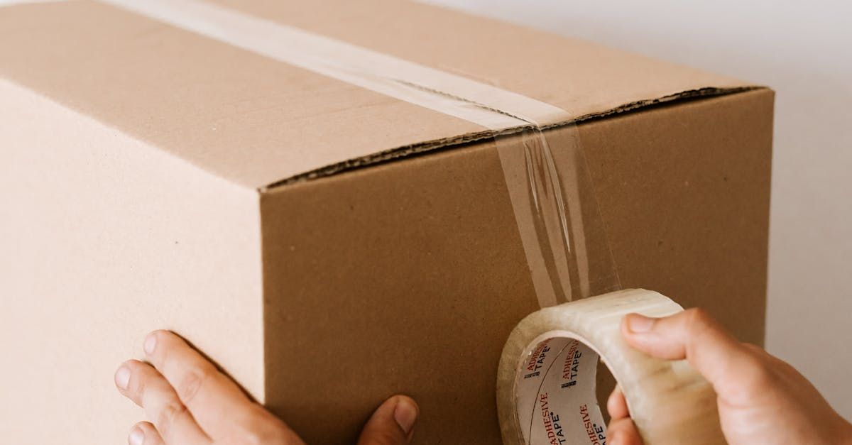 A person is taping a cardboard box with tape.