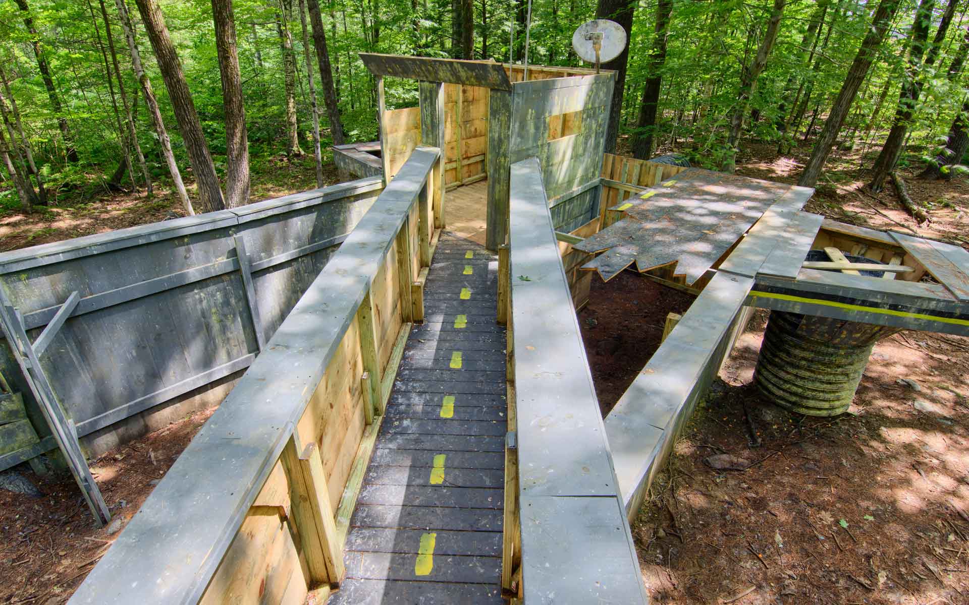 Wooden paintball course in a forest with walkways and structures.