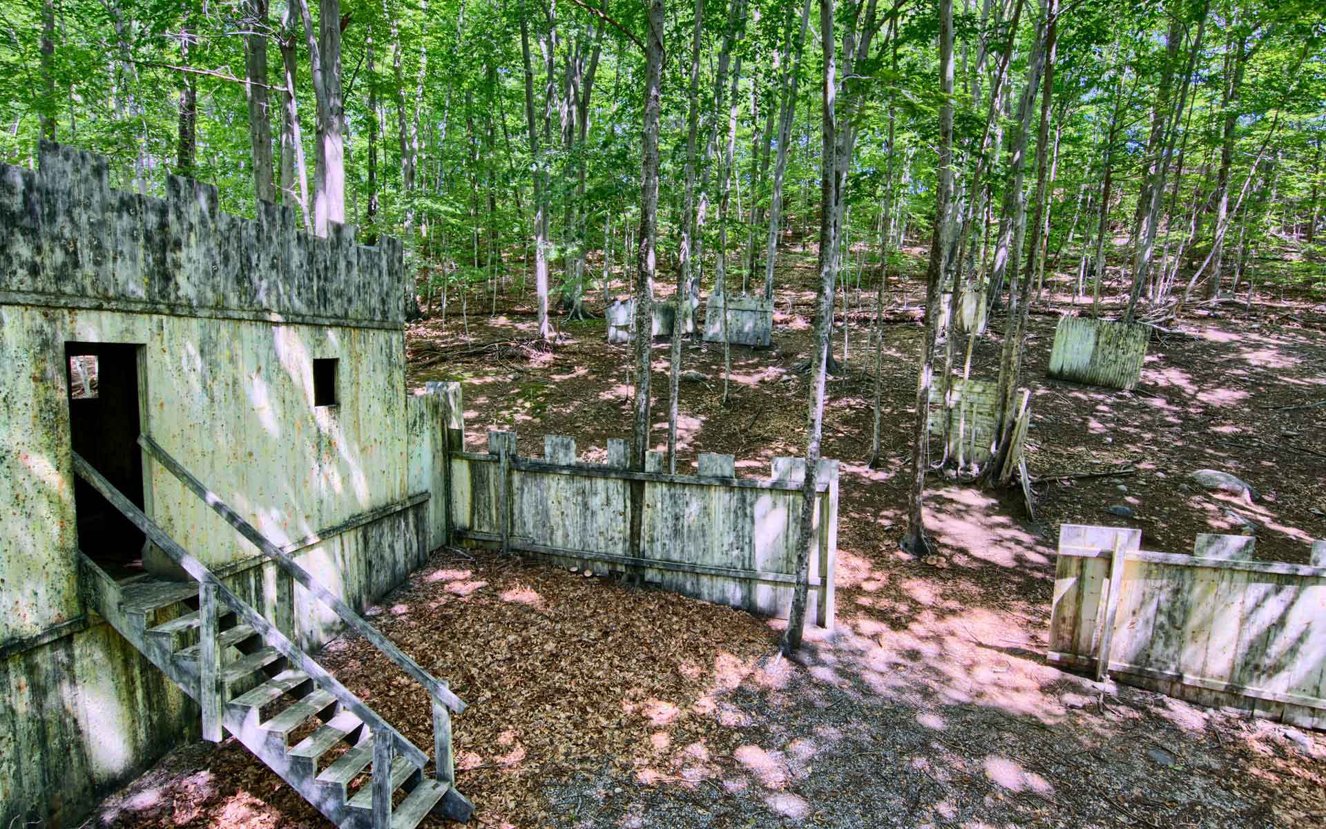 Paintball course with wooden structures in a forest, with stairs and walls.